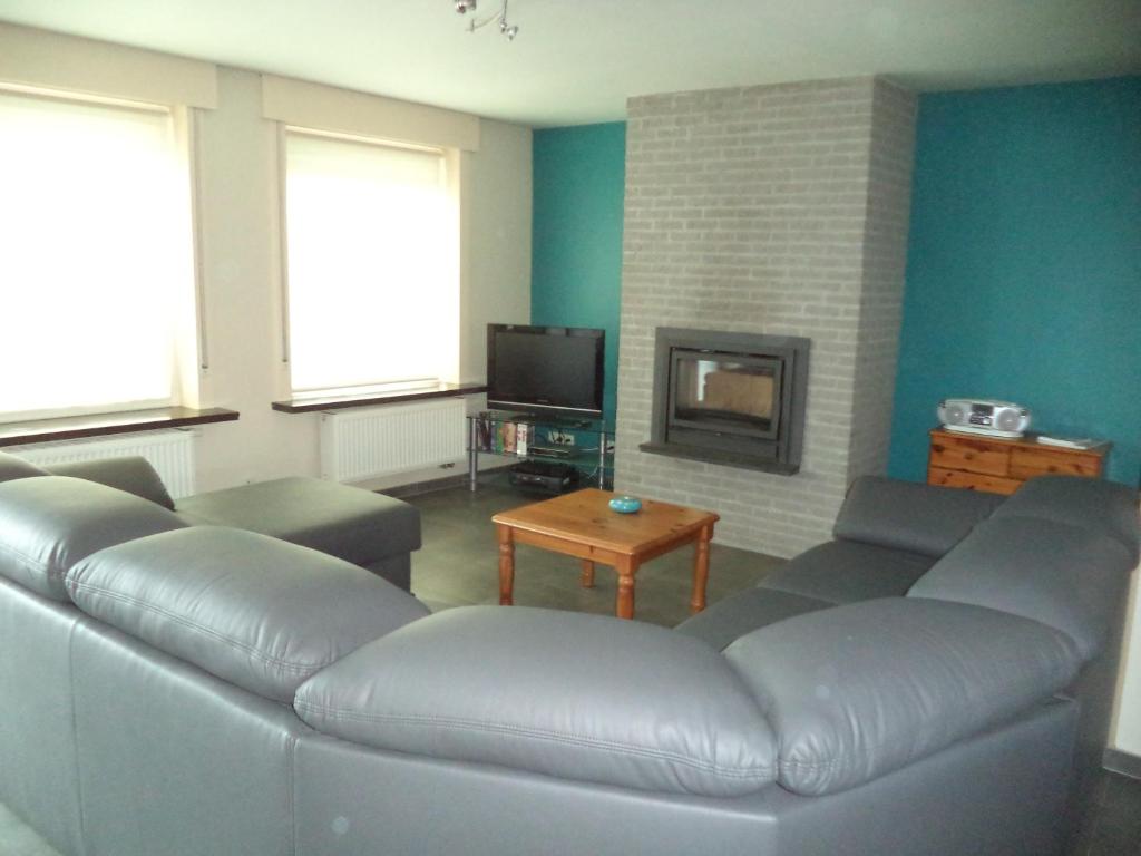 sala de estar con sofá de cuero y TV en De Zandhoorn, en De Panne