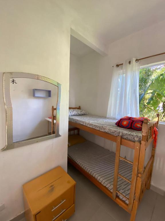 a room with a bunk bed with a mirror and a window at Xixová Hostel in São Vicente