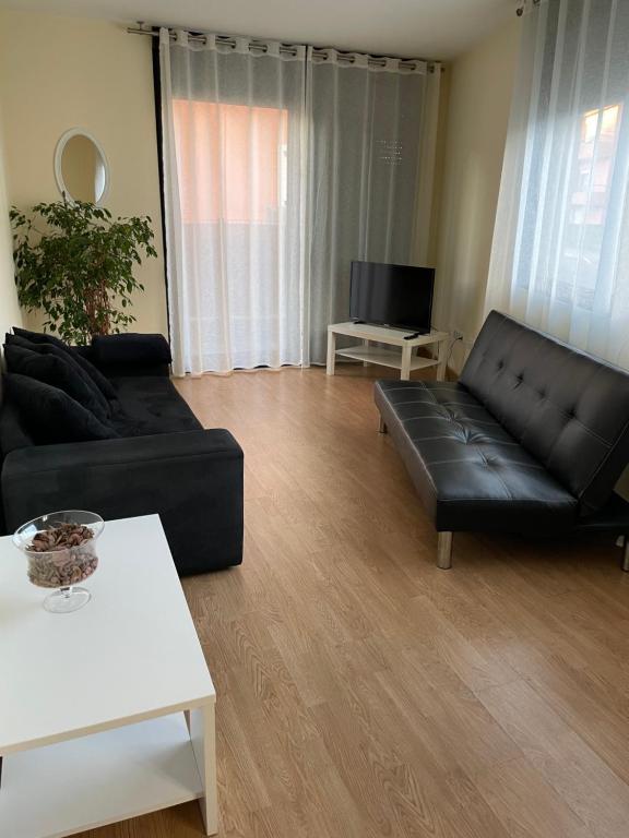 ein Wohnzimmer mit einem schwarzen Ledersofa und einem TV in der Unterkunft Apartamento en Ares in Ares