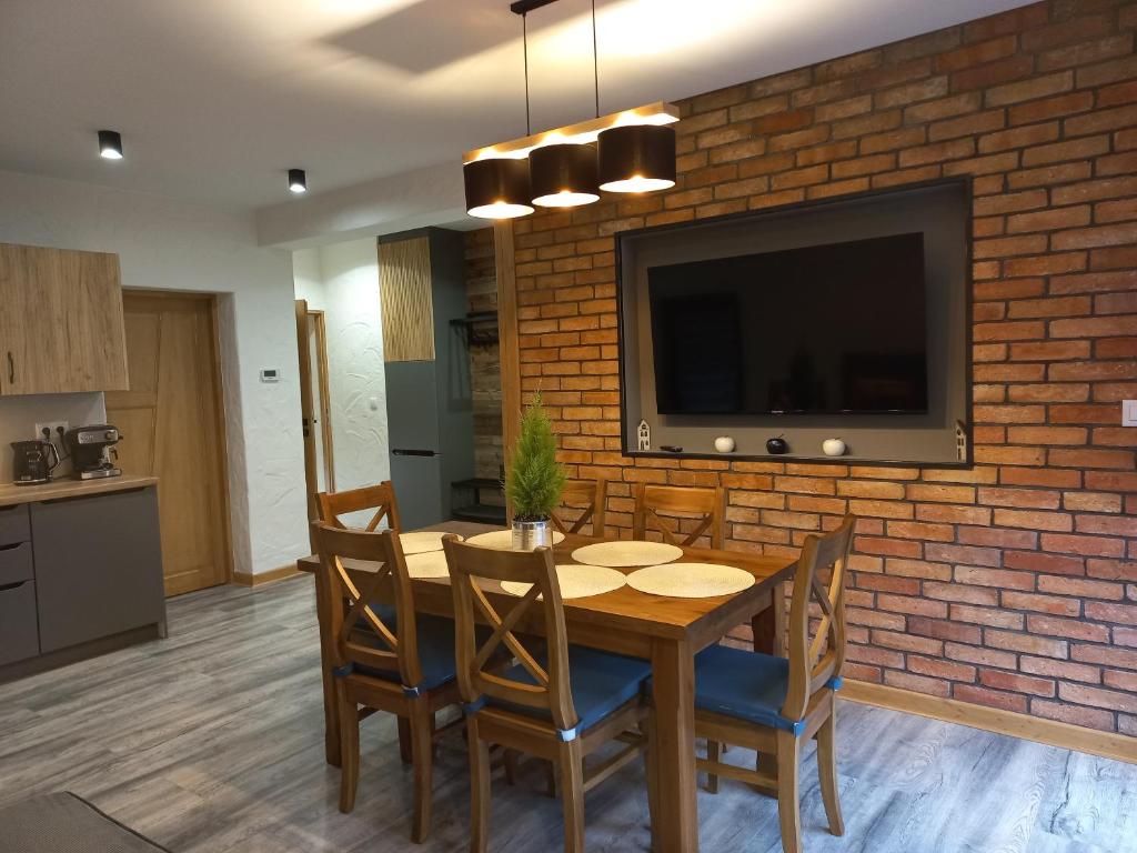 a dining room with a wooden table and a brick wall at ARAMIKA apartamenty in Szklarska Poręba