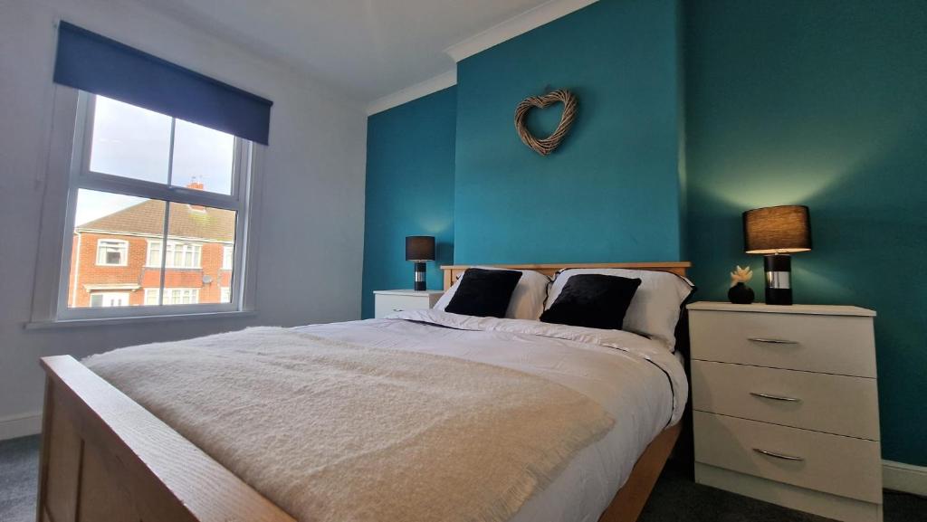 a bedroom with a bed with a blue wall at Cosy home perfect for families and contractors with free parking in Darlington