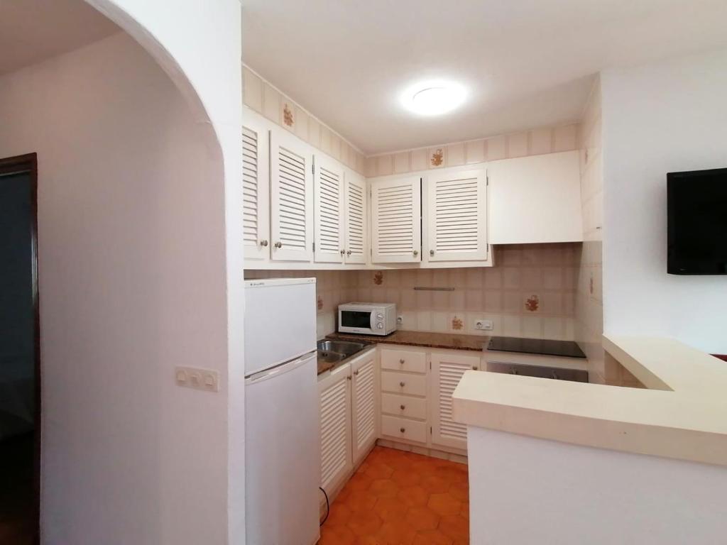 a kitchen with white cabinets and a white refrigerator at Apartamento colibrí in Alaior