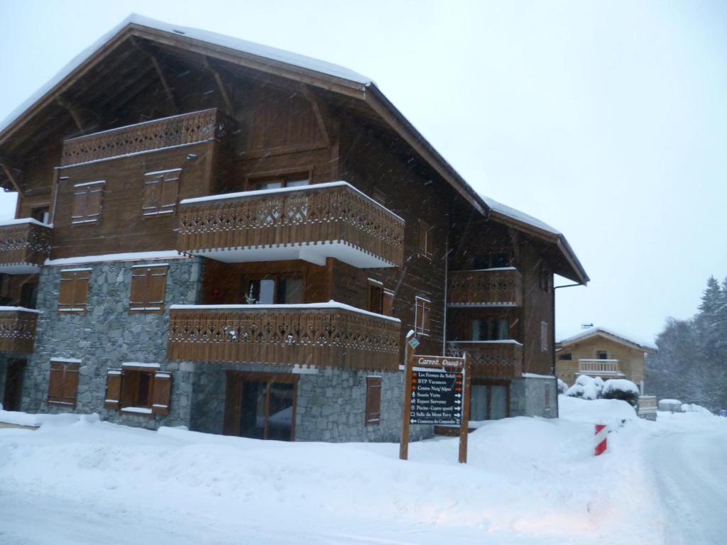 un grand bâtiment en bois avec de la neige au sol dans l'établissement Lucada Les Carroz, aux Carroz d'Arâches