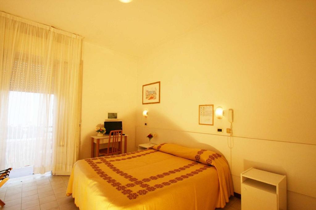 a bedroom with a yellow bed and a window at Hotel Eureka in Rimini