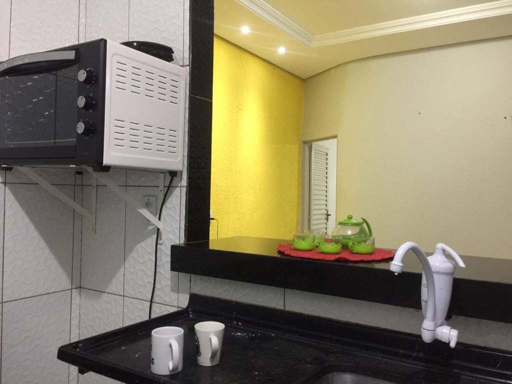 eine Küche mit einer Spüle, einer Mikrowelle und einem Spiegel in der Unterkunft HOSTEL D´ SALLES (PRÓXIMO AO AEROPORTO) in Palmas