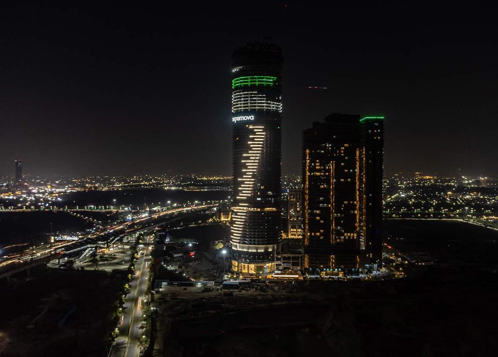 a tall building with green lights on it at night at The Opulence Suite 41st Floor City View in Noida