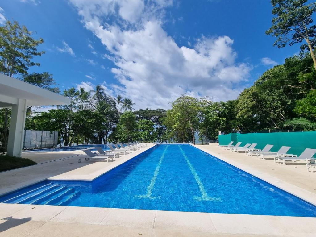 a swimming pool with lounge chairs and a blue sky at Punta Esmeralda by Punta Leona in Puntarenas