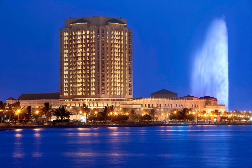 a large building next to a body of water at night at The Ritz-Carlton Jeddah in Jeddah
