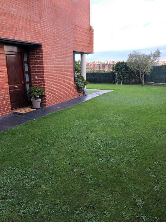 a red brick building with a door and a grass yard at Villa Mina in Camargo