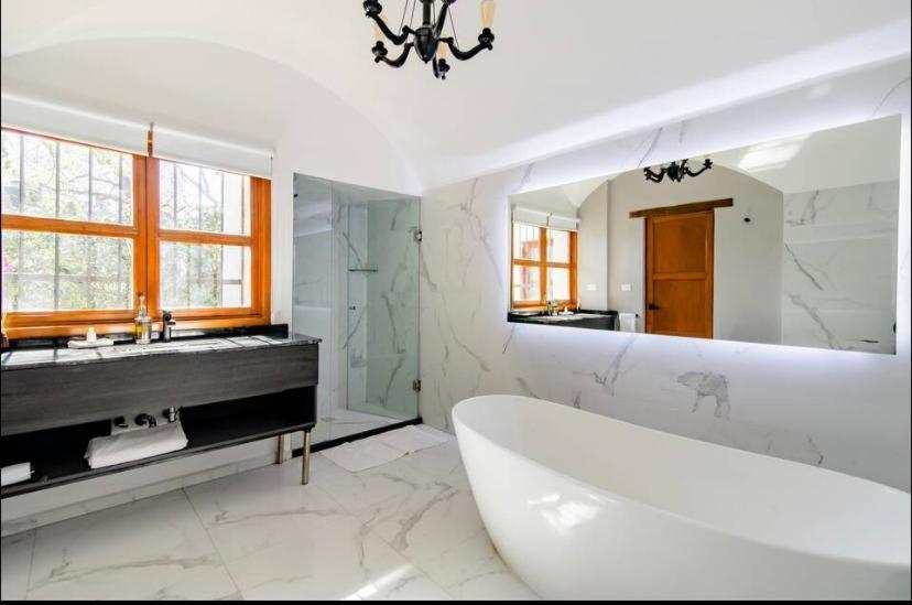 a white bathroom with a tub and a large mirror at Siete Puertas Coyoacán in Mexico City