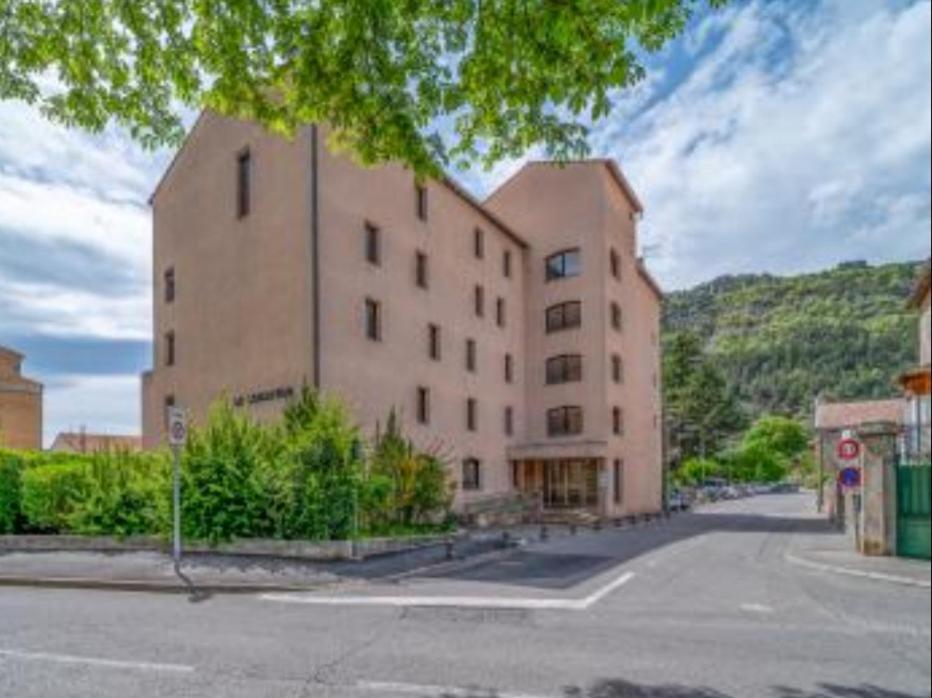 um grande edifício de tijolos ao lado de uma rua em Grand studio confortable jusqu'à 4 personnes em Digne-Les-Bains