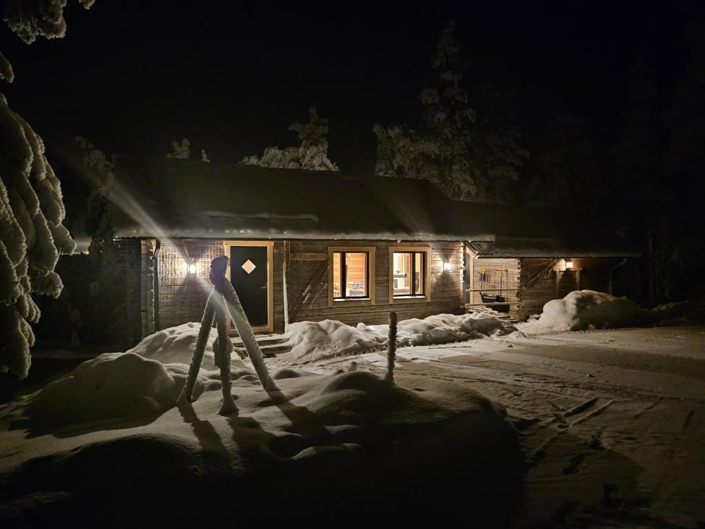 a person standing in the snow in front of a cabin at Hilltop Villa at Lake Porontima in Kuusamo