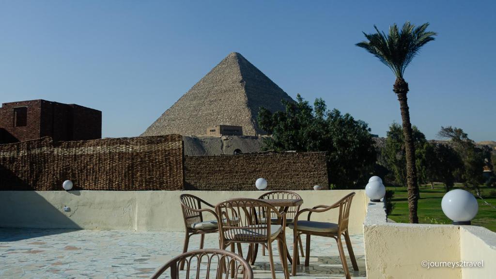 開羅的住宿－Golf Pyramids View，金字塔前的一组椅子和一张桌子