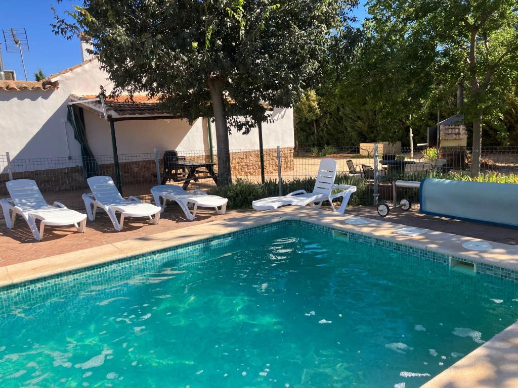 a swimming pool with chairs and a table and a picnic table at La Huerta el Bao in Alhambra
