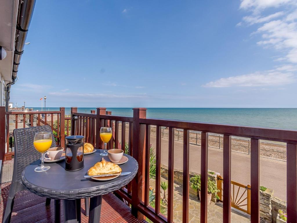 a table with two glasses of wine on a balcony overlooking the beach at 2 Bed in Bexhill-on-Sea 60137 in Bexhill
