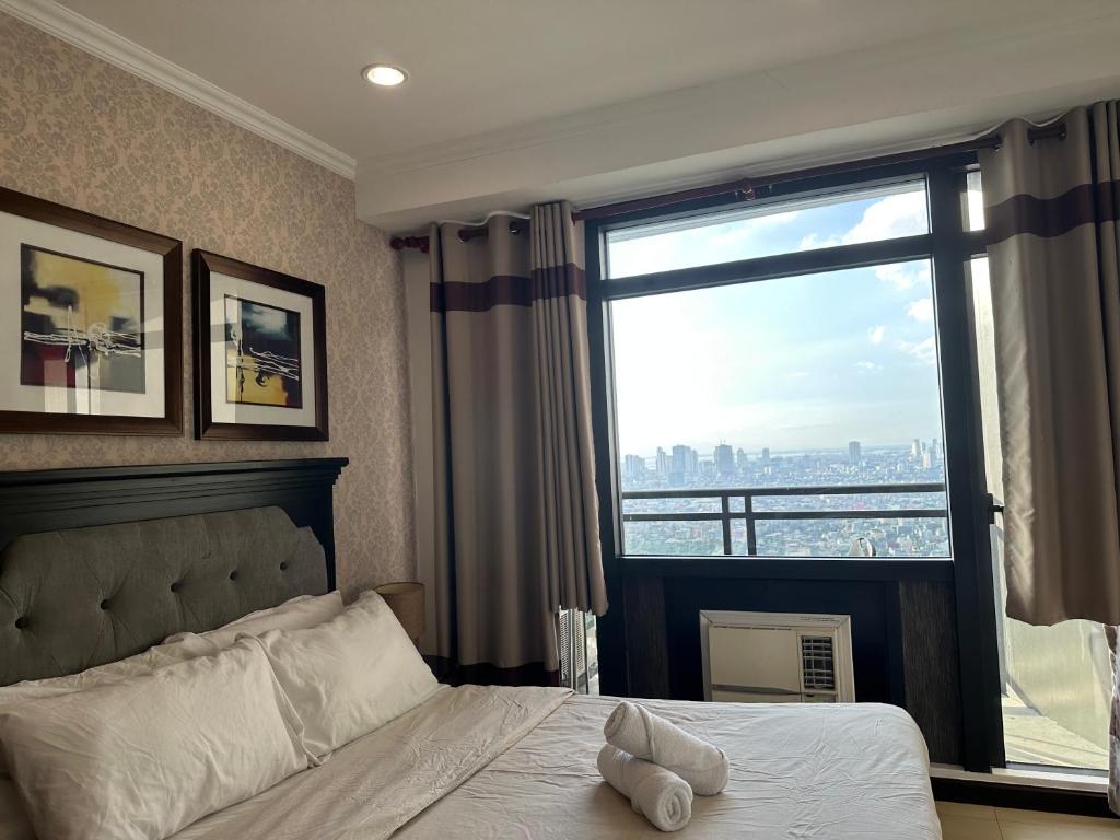 Gramercy Residences 46th Floor 1 Bedroom Sunset View في مانيلا: غرفة نوم بسرير ونافذة كبيرة