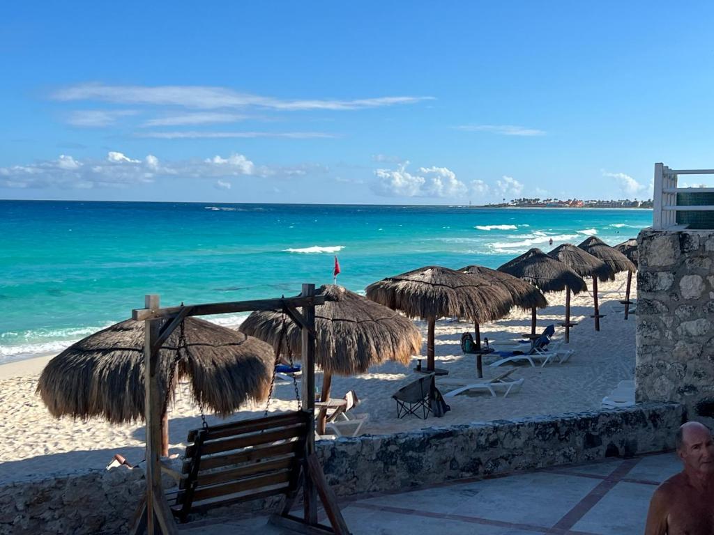 ein Strand mit vielen Strohschirmen und dem Meer in der Unterkunft Spectacular Beach Romantic Sunset Lagoon View Studio in Cancún