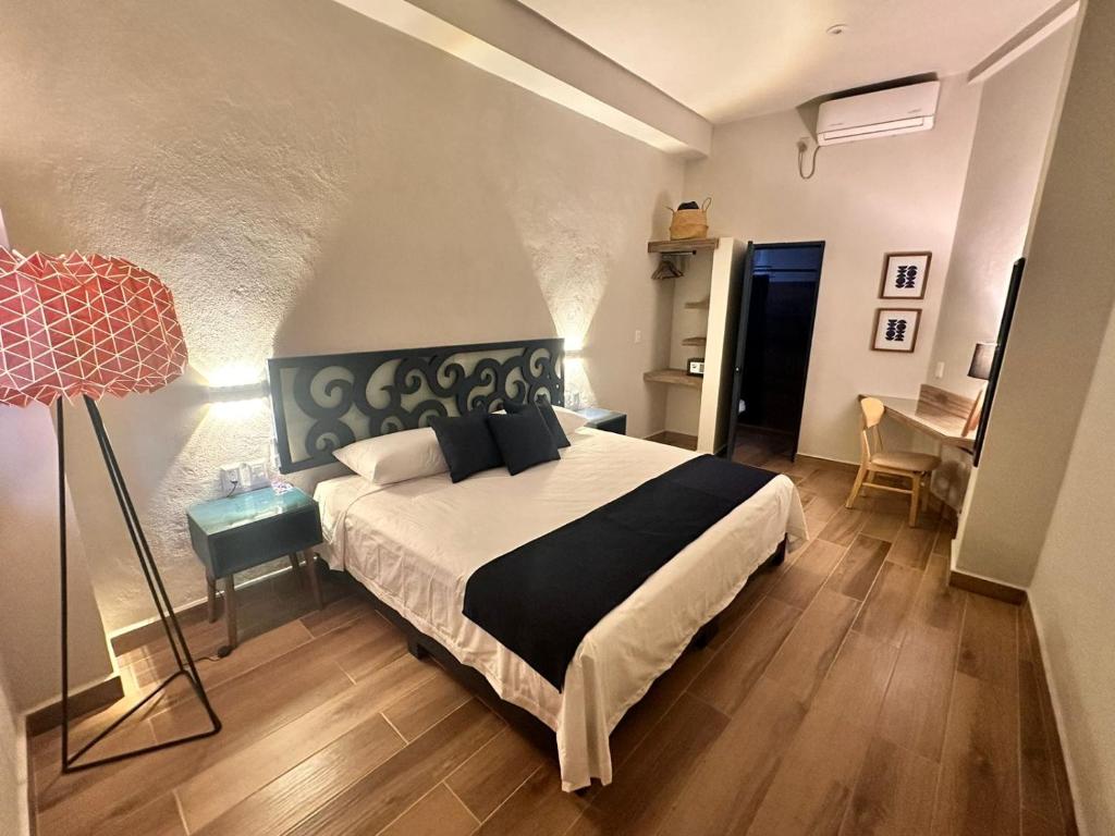 een slaapkamer met een bed, een lamp en een bureau bij Centrico House in Taxco de Alarcón