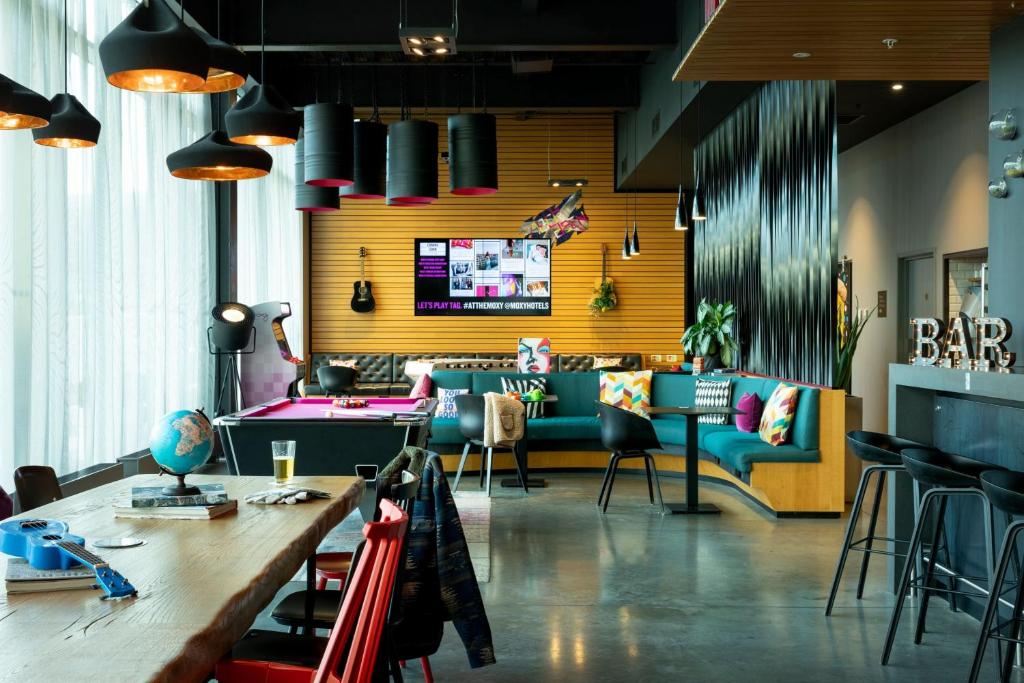 a restaurant with a bar with a table and chairs at Moxy Aberdeen Airport in Dyce