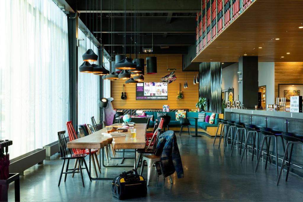 a restaurant with tables and chairs and a bar at Moxy Aberdeen Airport in Dyce