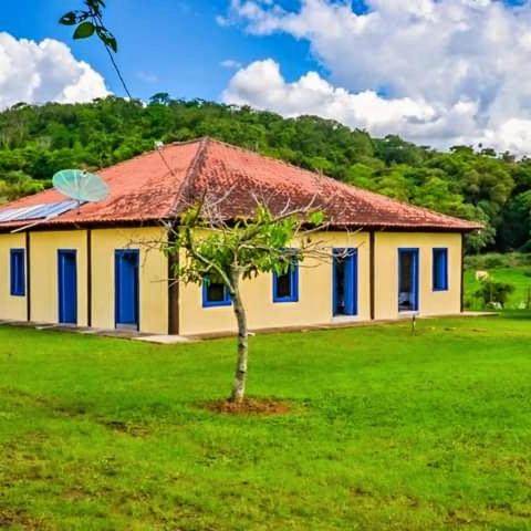 a yellow house with a tree in front of it at Casas da Mantiqueira in Bueno Brandão