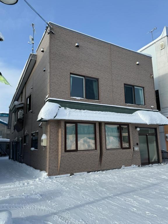 un edificio con nieve en el suelo delante de él en 名寄ベース en Nayoro