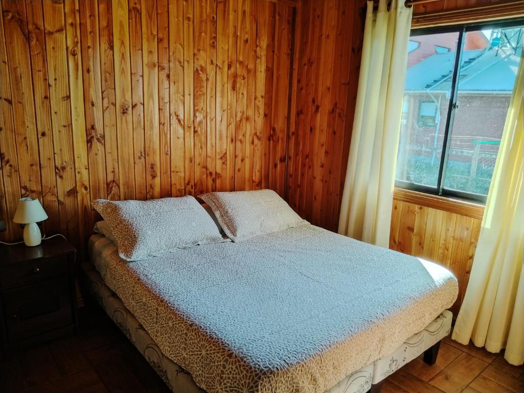 Ce lit se trouve dans un dortoir doté d'un mur en bois. dans l'établissement Cabaña 4 personas Lanco centro, à Lanco