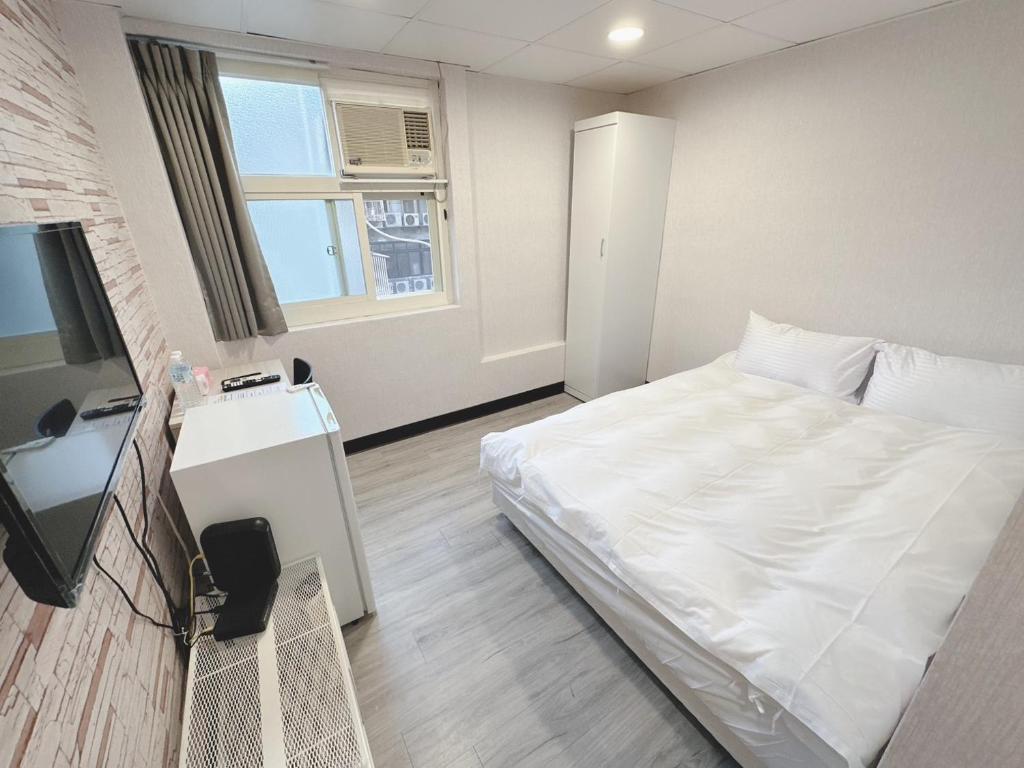 台北的住宿－新獅城商務旅店New Lion City Hotel，卧室配有白色的床和电视。