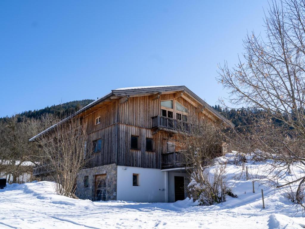 un grand bâtiment en bois dans la neige avec des arbres dans l'établissement Hexenwasser, à Söll