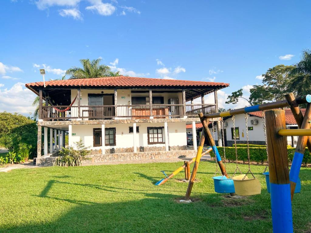 ein Haus mit einem Hof mit Spielplatz in der Unterkunft Finca Hotel Palmas Del Edén in Armenia