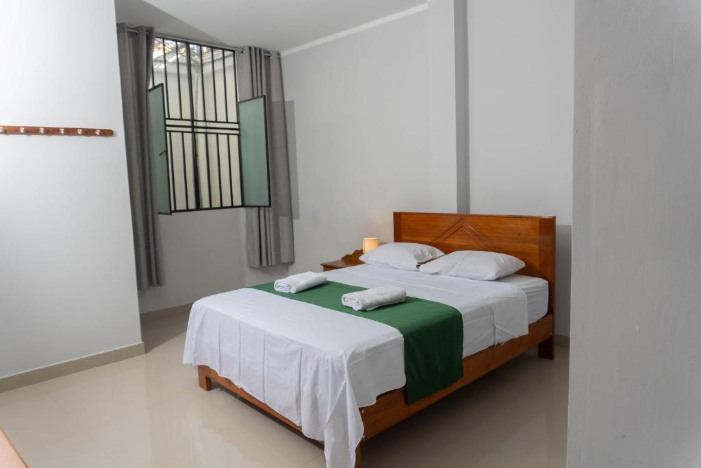 sypialnia z łóżkiem z białą pościelą i oknem w obiekcie Hospedaje Humazapa Tarapoto, San Martín w mieście Tarapoto