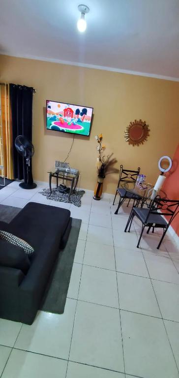 sala de estar con sofá y TV de pantalla plana en Finest Accommodation Jacaranda #528 Stem St Catherine en Spanish Town