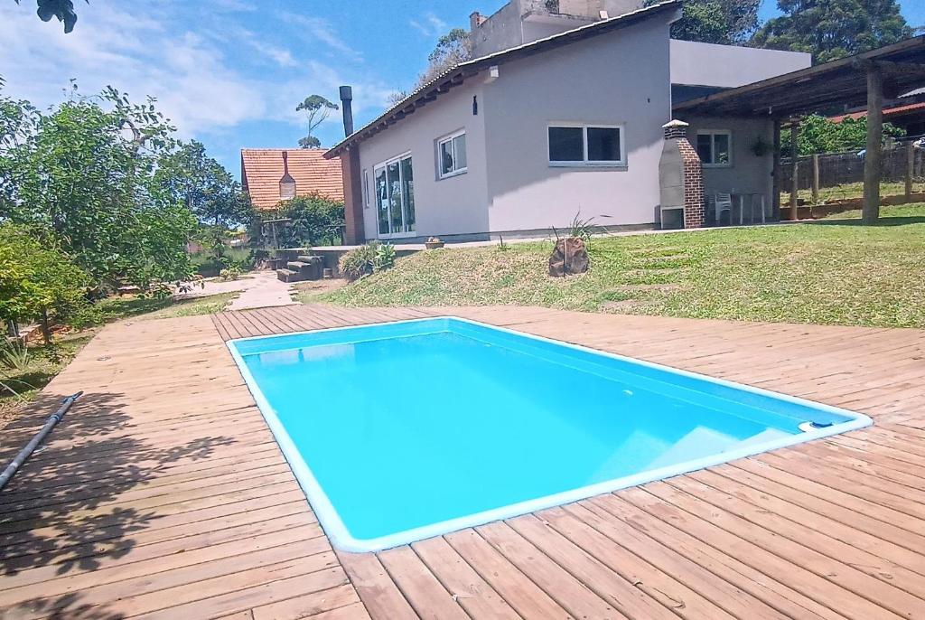 a blue swimming pool in front of a house at Chalé em Torres Recanto Estelar in Torres