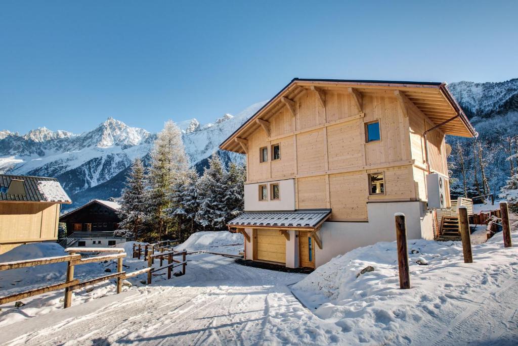 a wooden house in the snow with mountains in the background at Chalet Belle des Neiges - Alpes Travel - Sleeps 9 in Les Houches