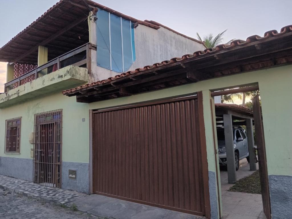une maison avec une porte de garage en bois et un balcon dans l'établissement Casa de Férias Arborizada, à Canavieiras