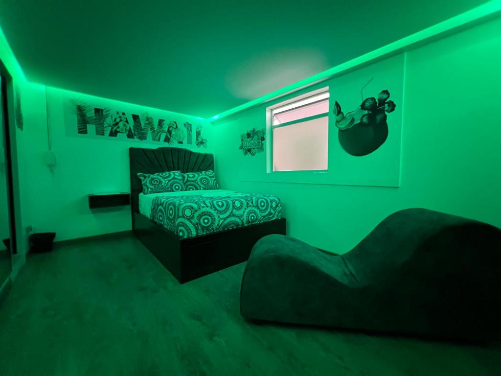 Grünes Zimmer mit einem Bett und einem Stuhl in der Unterkunft Dubai motel vip in Bogotá