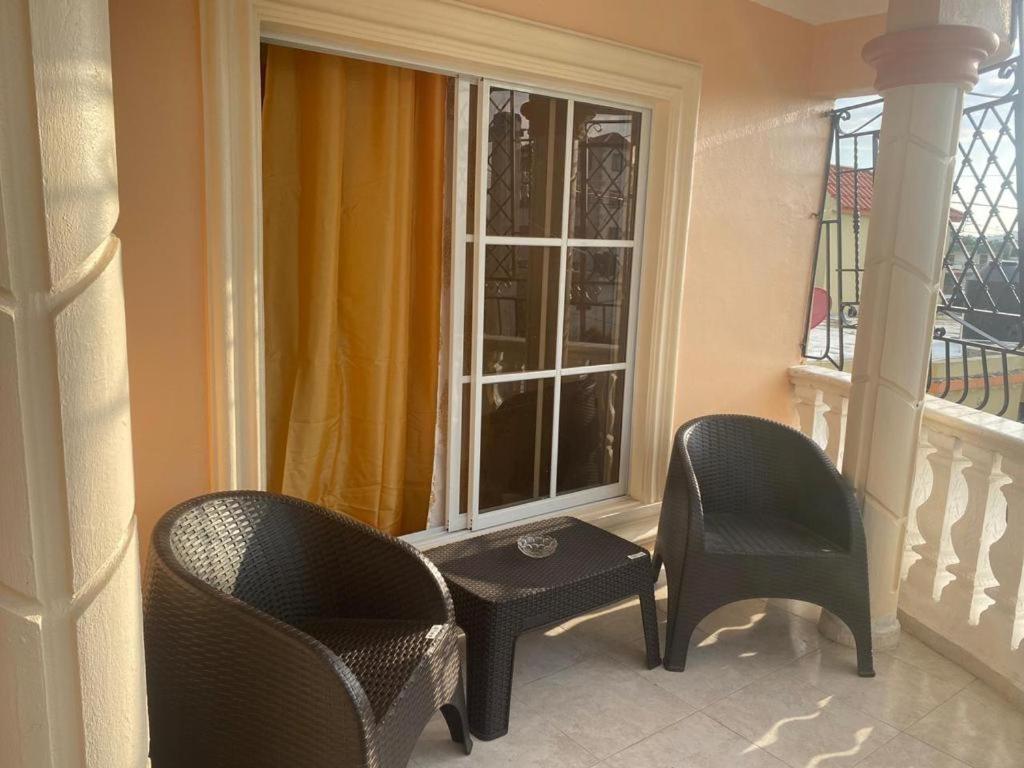 ein Balkon mit zwei Stühlen, einem Tisch und einem Fenster in der Unterkunft Quiet space in San Cristóbal