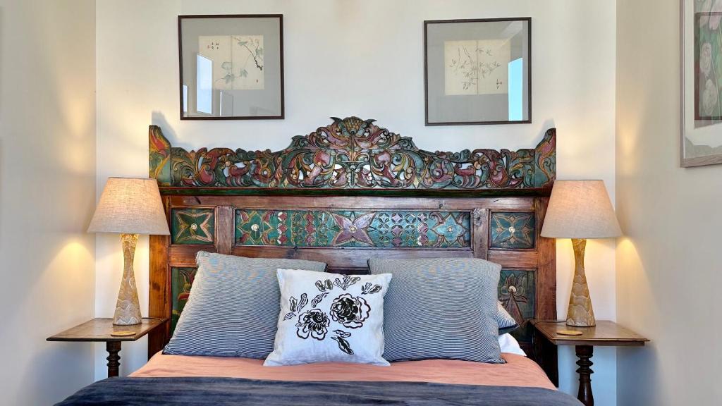 uma cama com uma cabeceira de madeira e 2 candeeiros em The Whitestone em Oamaru