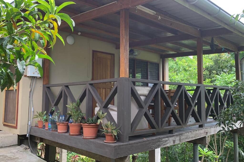 a wooden porch with potted plants on it at Canopy cottage in Honiara