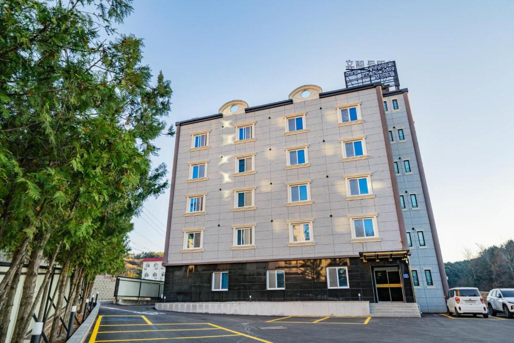 a large gray building with blue windows on a parking lot at Hotel gongjicheon 2 in Chuncheon