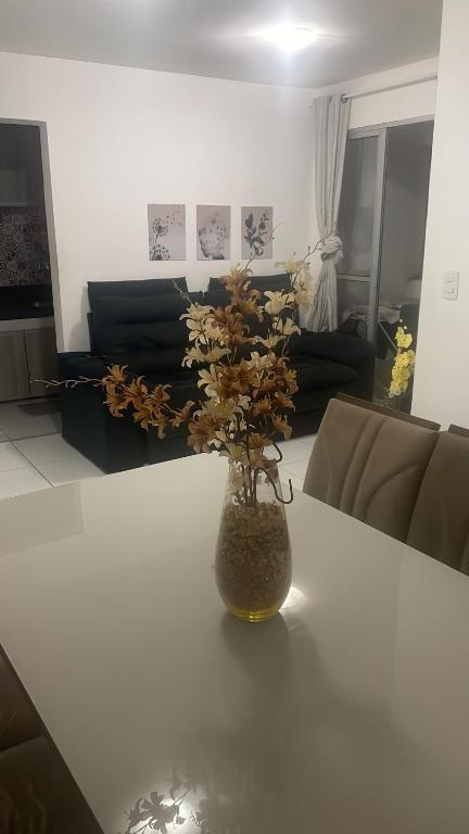 a vase with flowers on a table in a living room at Apartamento Tupa in Propriá