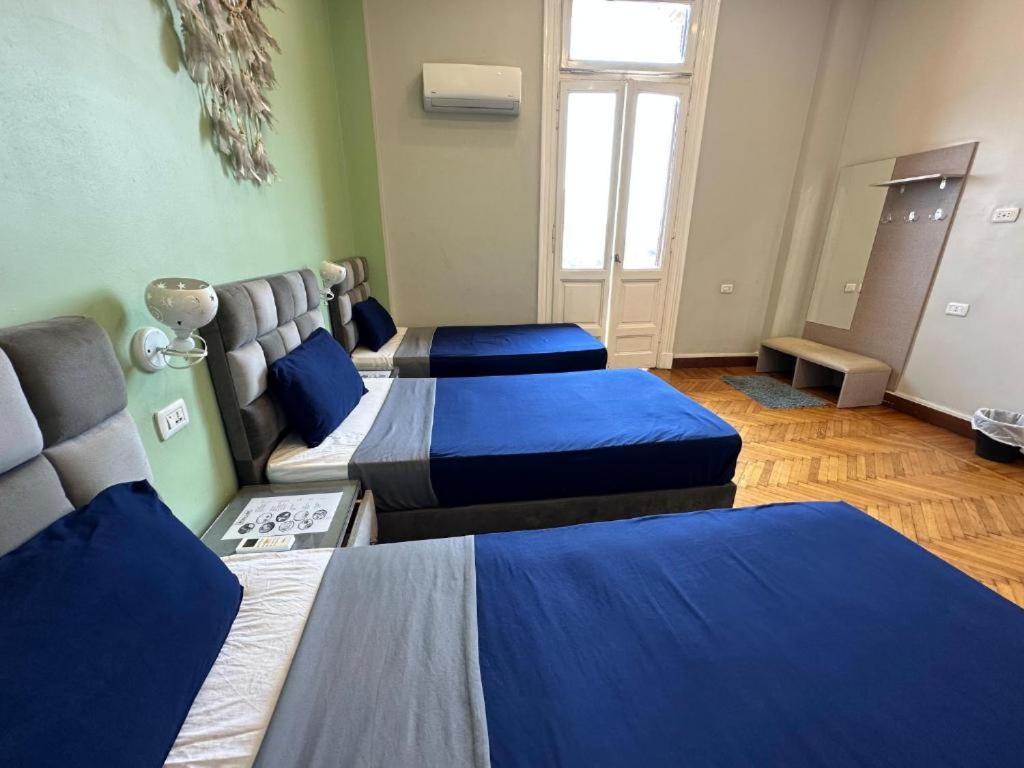 3 Betten in einem Zimmer mit blauer Bettwäsche in der Unterkunft Cairo Hub in Kairo