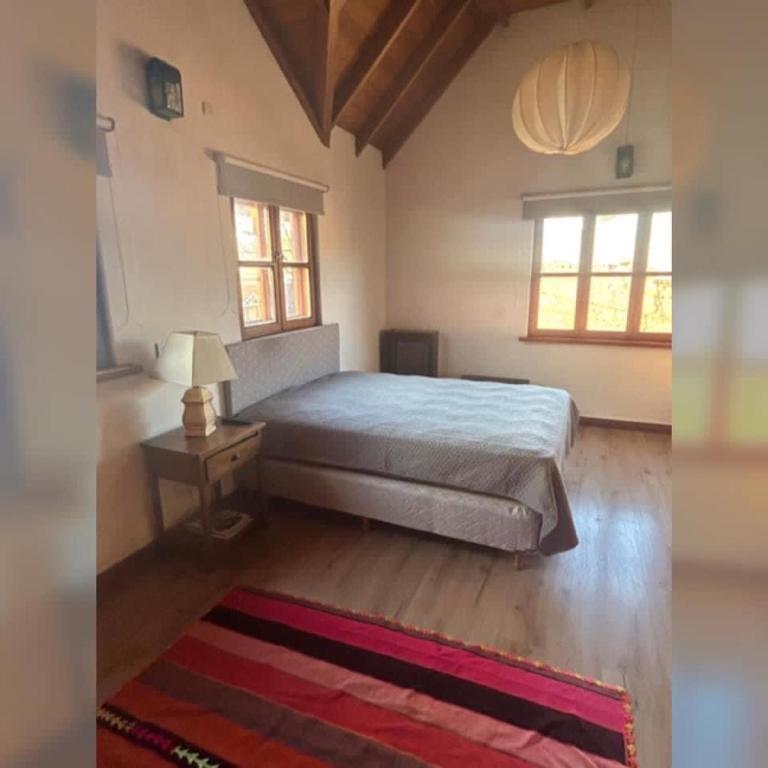a bedroom with a bed and a table and windows at Colibrí Tempo in Esquel