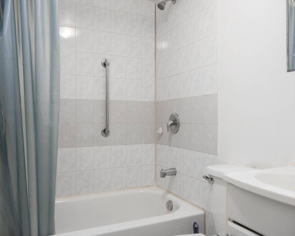 a white bathroom with a tub and a sink at Cozy studio apartment - 240 in Montréal