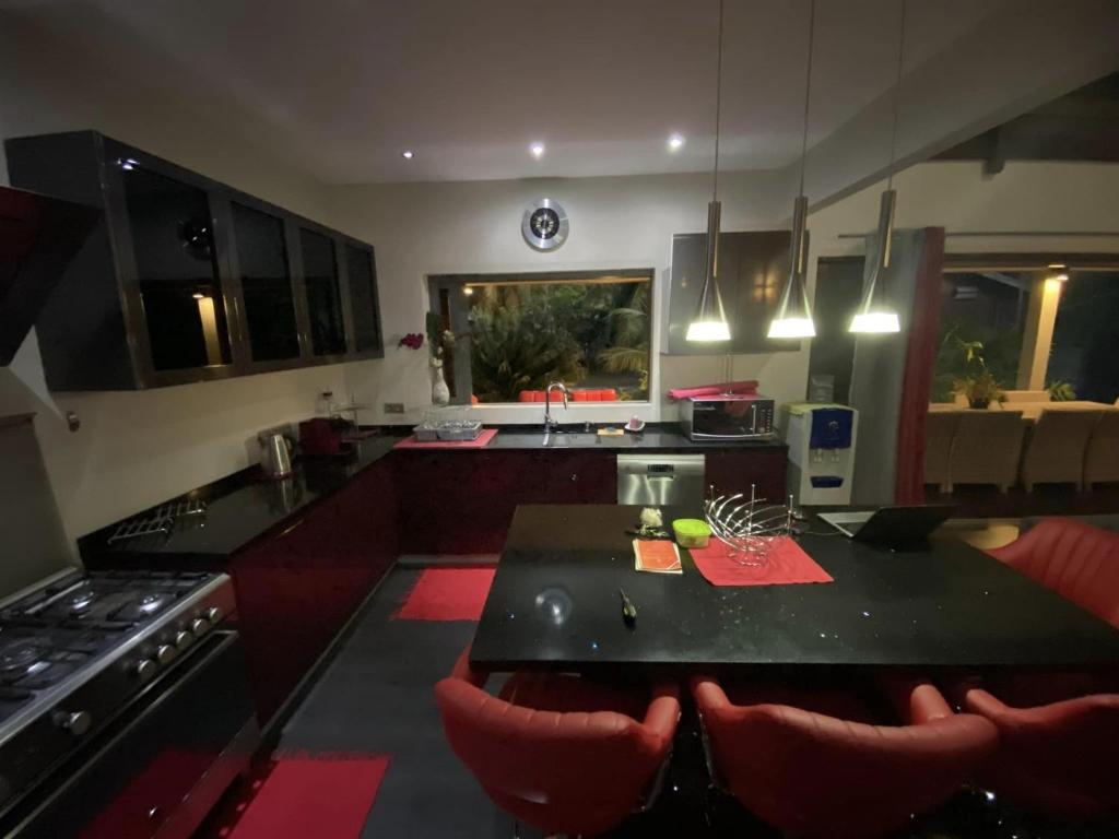 uma cozinha com uma mesa preta e cadeiras vermelhas em MOOREA - Villa Tiahura em Hauru