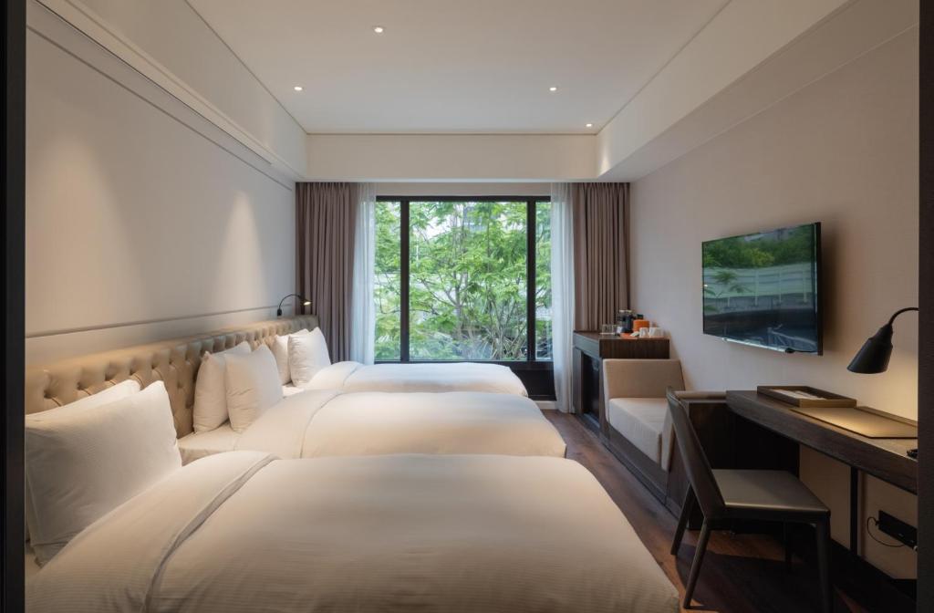 a hotel room with three beds and a desk at Hotel Mvsa+Michelin 2 Starred Molino de Urdàniz in Taipei