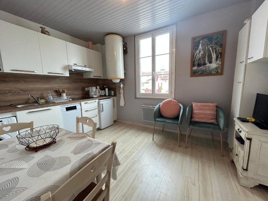 a kitchen with white cabinets and a table and chairs at Appartement Urrugne, 2 pièces, 2 personnes - FR-1-239-508 in Urrugne