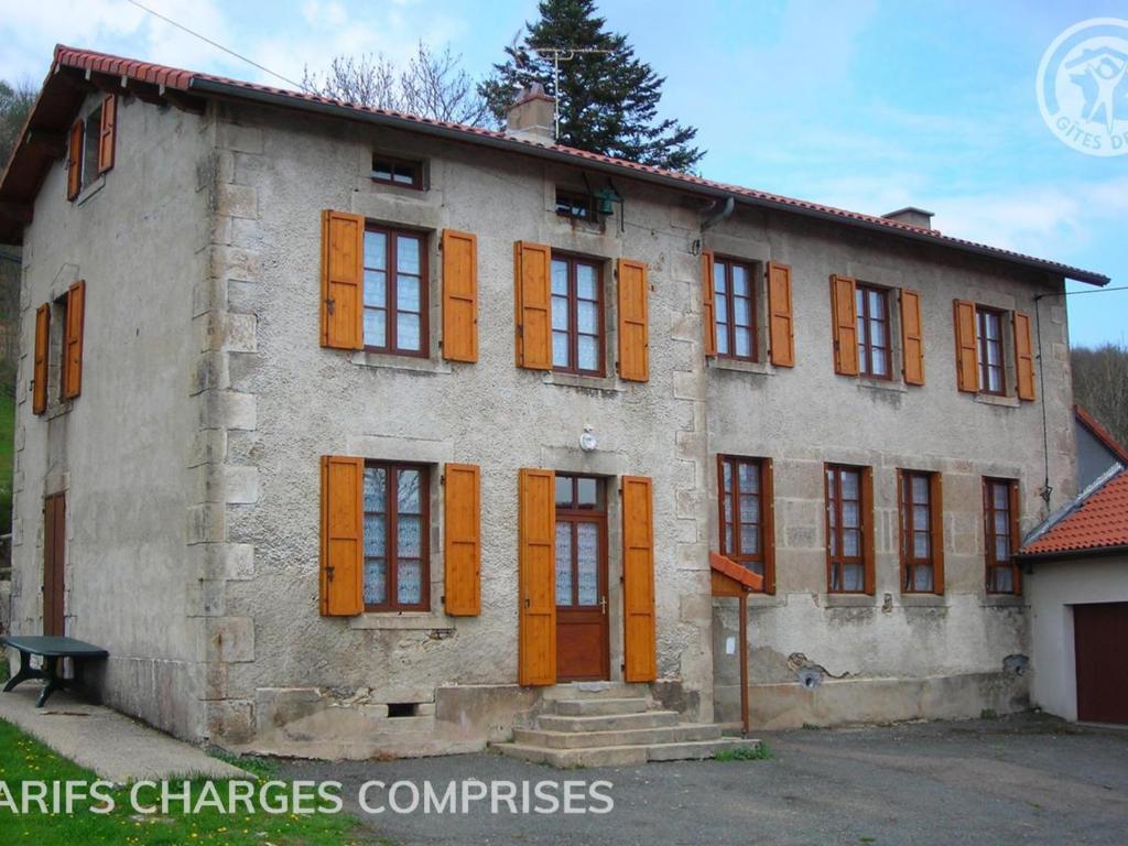 un viejo edificio con persianas naranjas. en Gîte La Chambonie, 4 pièces, 6 personnes - FR-1-496-197, en La Chambonie