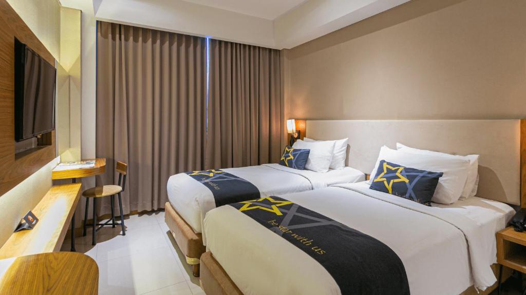 a hotel room with two beds and a television at Yellow Star Ambarukmo Hotel in Yogyakarta