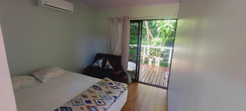 ein Schlafzimmer mit einem Bett und einem Stuhl sowie einem Balkon in der Unterkunft ENCANTADORA CABAÑA DEL BOSQUE in San José